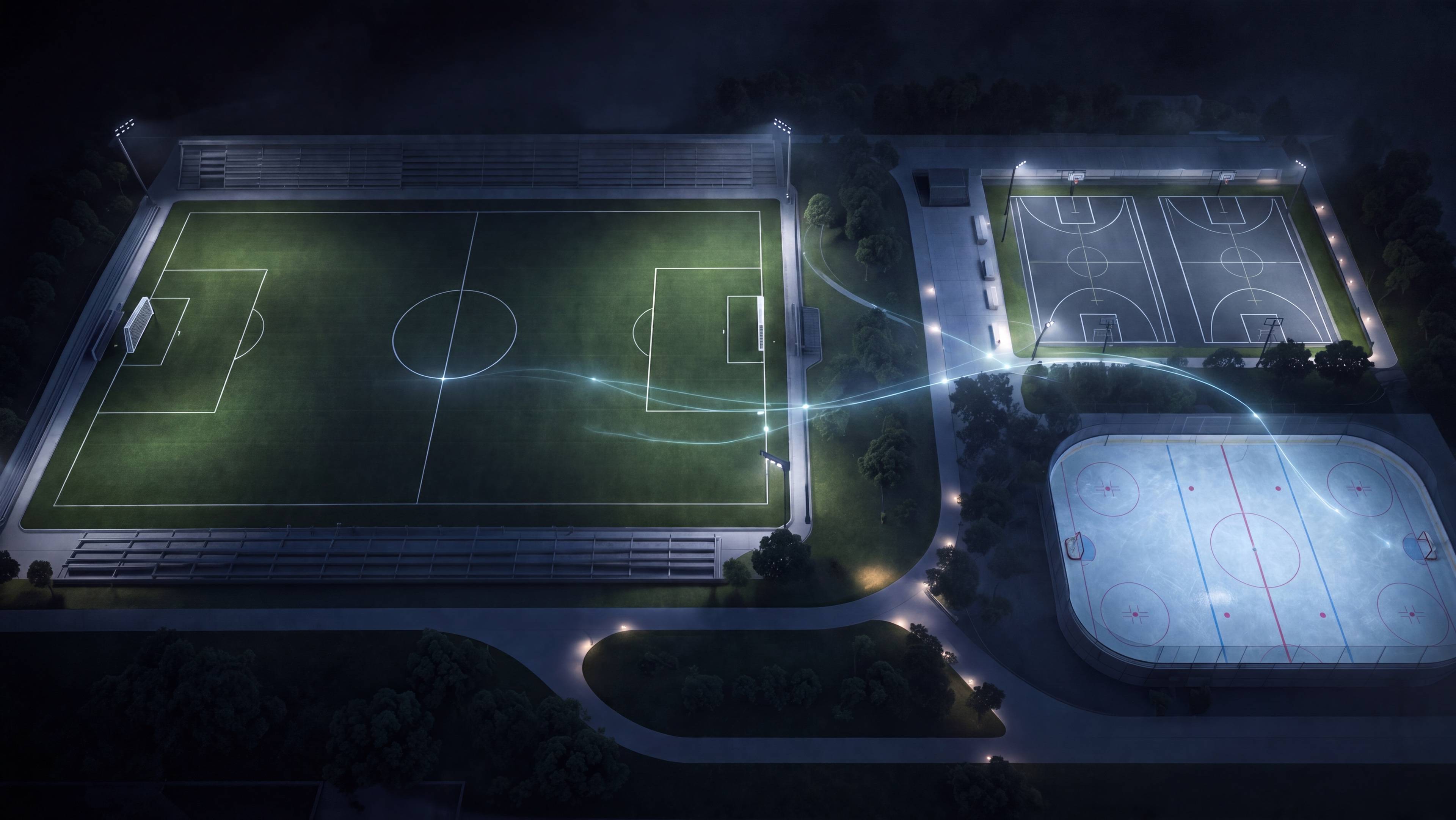 Aerial night view of a multi-sport complex with soccer field, basketball courts, and ice rink, connected by light trails